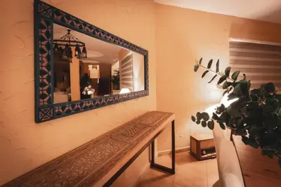 a mirror on a wall with a bench and a plant at The Precious Villa in Sowayma