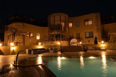 a large building with a swimming pool at night at The Precious Villa in Sowayma