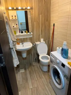a bathroom with a toilet and a sink and a washing machine at My Cosy little place in Amman