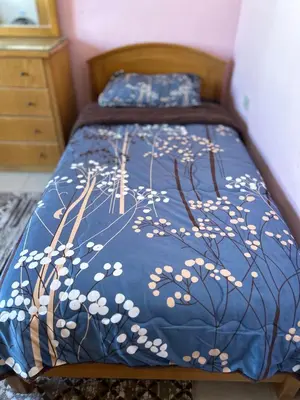 a bed with a blue comforter with white flowers on it at Eva house Lovely 3 bedrooms unit in great location in Amman for families in Amman
