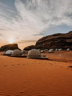 a group of tents in the desert with the sunset at orbit camp 2 in Wadi Rum