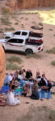 a group of people sitting on blue mats in front of a truck at Shakria Bedouin Life Camp in Wadi Rum