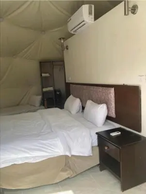 a bedroom with a large bed and a night stand at Lukasa camp Wadi Rum in Wadi Rum