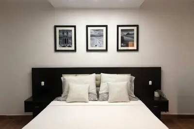 a bedroom with a white bed with four pictures on the wall at Luxury Apartment in Awesome Location in Amman in Amman