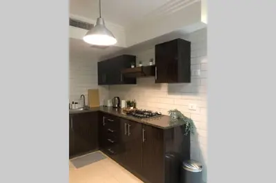 a kitchen with brown cabinets and a counter top at Luxury Apartment in Awesome Location in Amman in Amman