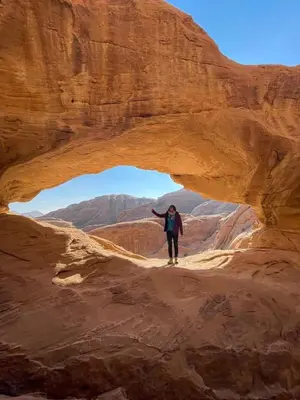 a woman walking through an arch in the desert at Rum Rayan magic camp in Wadi Rum