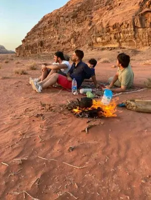 a group of people sitting around a fire in the desert at moon city with jeep trips in Wadi Rum