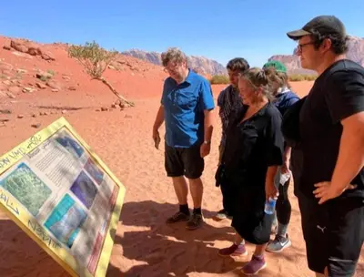 a group of people looking at a sign in the desert at moon city with jeep trips in Wadi Rum