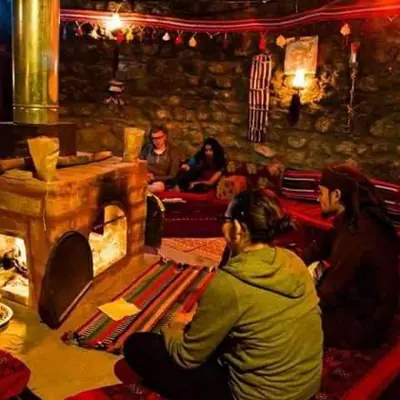 a group of people sitting in a room with a fireplace at Petra Bedouin House 1 Attallah guest house in Wadi Musa