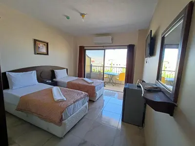 a hotel room with two beds and a balcony at Baraka Al Aqaba Hotel Suites in Aqaba