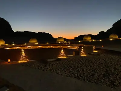 a bridge with lights on the beach at night at Star Camp in Wadi Rum