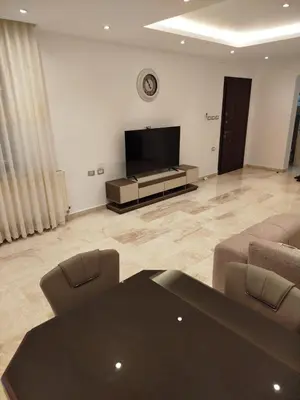 a living room with a table and a flat screen tv at Executive Apartments in Amman