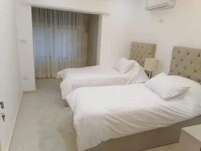 two beds in a hotel room with white sheets at Executive Apartments in Amman