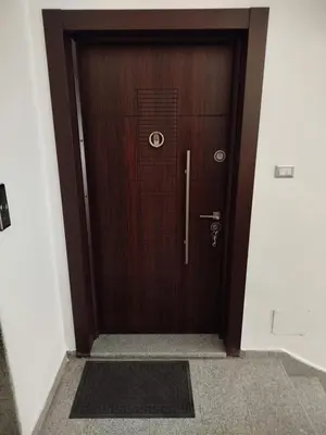a wooden door in a building with a mat in front at Executive Apartments in Amman
