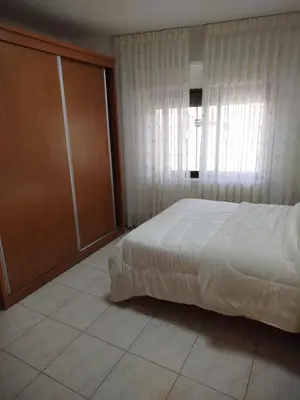 a bedroom with a white bed and a window at Executive Apartments in Amman