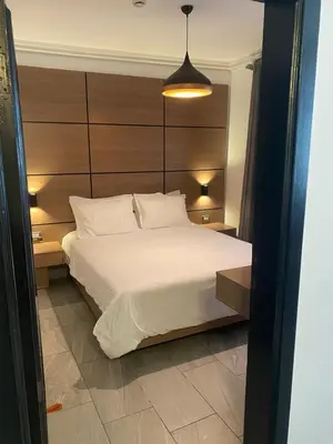 a bedroom with a white bed with a wooden headboard at flamingo hotel irbid in Zabdah