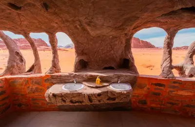 a stone bathroom with two sinks in a desert at Wadi Rum Cave Camping in Wadi Rum