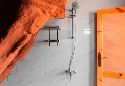 a bathroom with a shower with a microphone on the wall at Wadi Rum Cave Camping in Wadi Rum