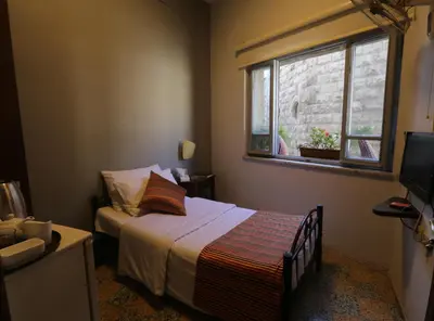a small bedroom with a bed and a window at Riviera Hotel in Amman