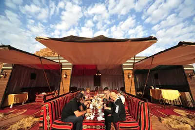 a group of people sitting at a long table at SunCity Camp in Wadi Rum