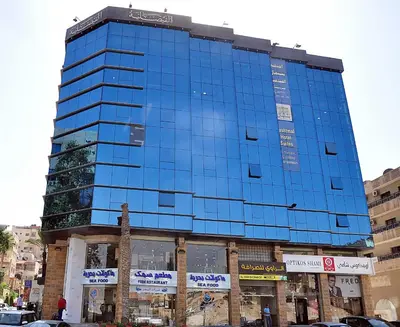 a tall blue building on a city street at Bashtamal Hotel Suites in Amman