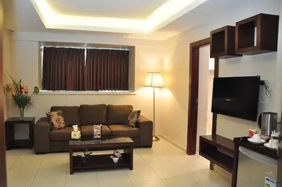 a living room with a couch and a flat screen tv at Bashtamal Hotel Suites in Amman