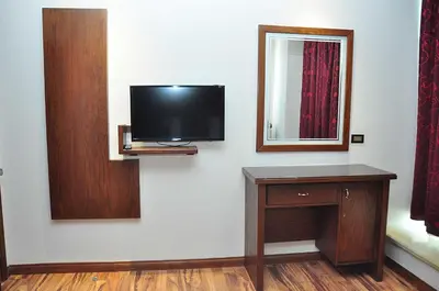 a room with a tv and a desk and a mirror at Bashtamal Hotel Suites in Amman
