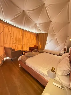 a bedroom with a large bed and a chair at Sunrise Luxury Camp in Wadi Rum