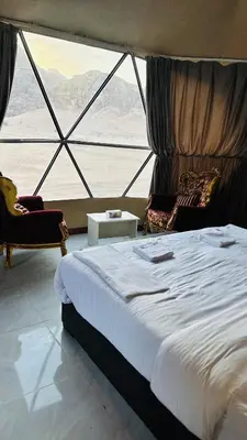 a large bed in a room with a large window at Rehana rum luxury camp in Wadi Rum
