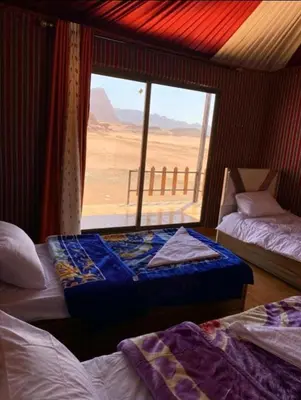 a room with two beds and a large window at Rehana rum luxury camp in Wadi Rum