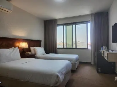 a hotel room with two beds and a large window at Amman Orchid Hotel in Amman