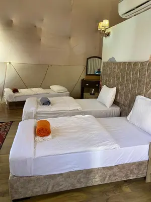 three beds in a room with white sheets at Montana Camp wadi rum in Wadi Rum