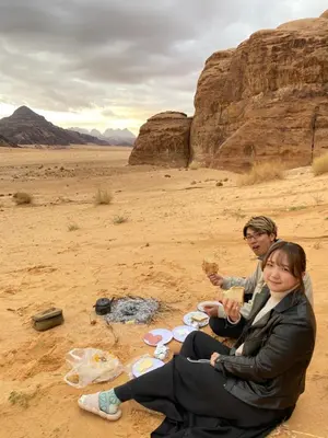 a man and woman eating food in the desert at Wadi Rum albasli in Wadi Rum