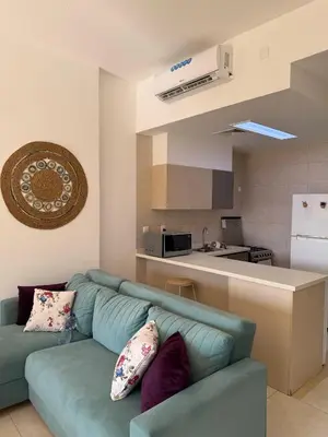 a living room with a blue couch and a kitchen at Rental unit in RAHA village compound, special view in Aqaba