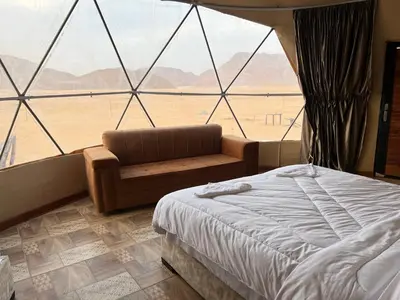 a bedroom with a bed and a couch in front of a window at Wadi Rum Oscar camp in Wadi Rum