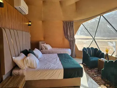 a bedroom with two beds and a large window at Wadi Rum Oscar camp in Wadi Rum