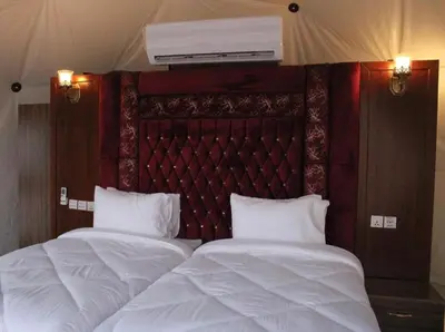 two beds with white sheets and a red headboard at Sun rise wadi rum camp in Wadi Rum