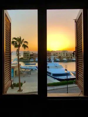 a window view of a marina with a sunset at Only FAMILIES - Tala Bay Resort Aqaba - Seafront one bedroom apartment in Aqaba