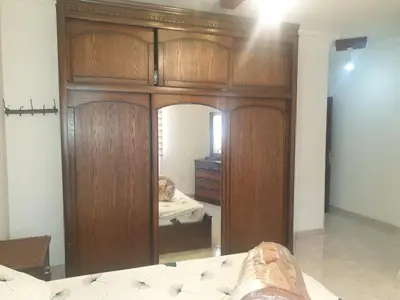 a bedroom with a wooden cabinet with a bed in it at شقة مفروشة فرش فاخر ٣ غرف نوم في طبربور عمان in Amman