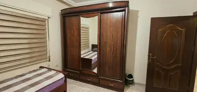 a bedroom with a wooden cabinet with a mirror at شقة مفروشة فرش فاخر ٣ غرف نوم في طبربور عمان in Amman