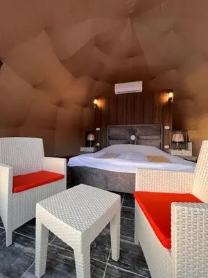 a bedroom with a large bed with chairs and tables at Orbit camp in Wadi Rum