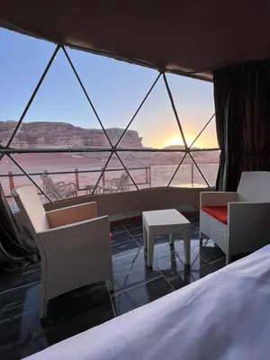 a room with a bed and chairs and a view of the ocean at Orbit camp in Wadi Rum