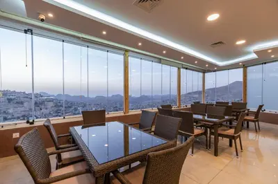 a restaurant with tables and chairs and large windows at Petra Elite Hotel in Wadi Musa
