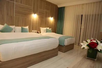 a hotel room with two beds and a vase of flowers at Turquoise Hotel in Aqaba