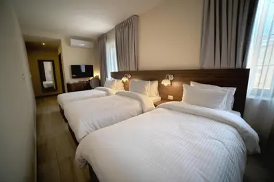 three beds in a hotel room with white sheets at Khan Khediwe Hotel in Amman