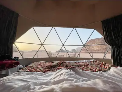 a bed in a room with a large window at wadi rum land mars in Wadi Rum