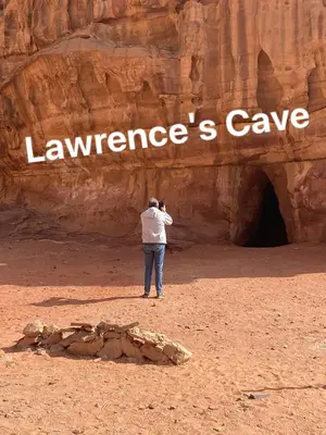 a man taking a picture of a cave in the desert at wadi rum land mars in Wadi Rum