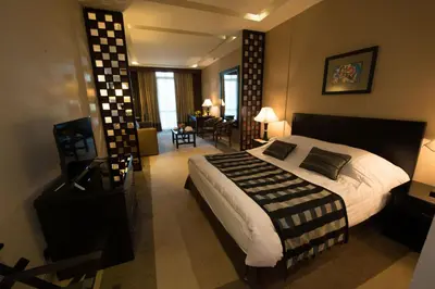 a bedroom with a large bed and a living room at Century Park Hotel in Amman