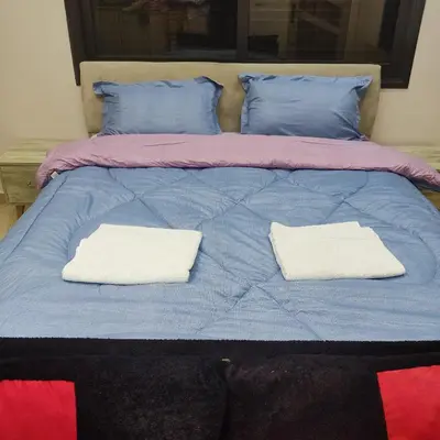 a blue bed with two white towels on it at Lotus housing for furnished apartments in Jerash
