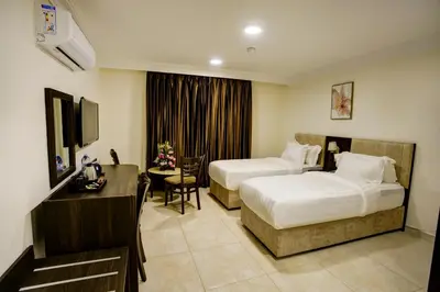 a hotel room with two beds and a desk at AQABA COAST HOTEL in Aqaba